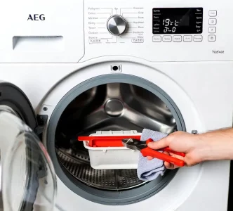 Vorsichtiges Öffnen eines klemmenden AEG Lavamat Flusensiebs mit einer Zange und Lappen zum Schutz.