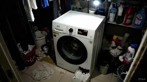 Handyfoto einer AEG Waschmaschine mit Fehlercode E20 im Display und geöffnetem Flusensieb.