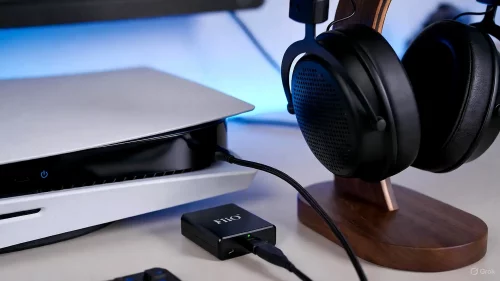 Nahaufnahme eines FiiO Q3 DAC, der über USB-C mit einer PlayStation 5 verbunden ist, um die Audioqualität zu verbessern.