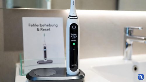 Eine Oral-B iO Zahnbürste auf einer Ladestation mit deutscher Displayanzeige zur Systemprüfung.