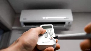 Drücken der CHK-Taste auf Toshiba Fernbedienung mit Kugelschreiber zum Auslesen von Fehlercodes.